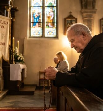 Obraz przedstawiający księdza modlącego się w kościele pełnym ludzi