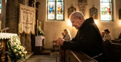 Obraz przedstawiający księdza modlącego się w kościele pełnym ludzi