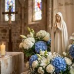 Niewielka figurka Matki Boskiej w kościele otoczona jest kwiatami, świecami i różańcem. W tle, choć nieostry, widoczny jest Chrystus na krzyżu.