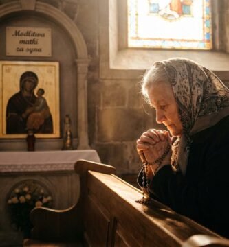 Zdjęcie starszej matki modlącej się w pustym kościele z obrazem Maryi w tle