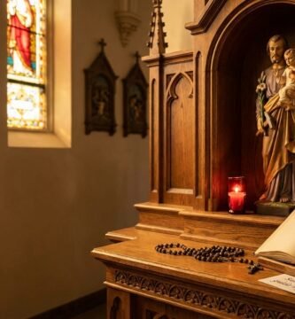 Obraz przedstawiający św. Józefa obok Jezusa wyrzeźbiony w drewnie wewnątrz kościoła, obok otwarta Biblia z tytułem artykułu