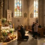 Obraz wnętrza kościoła z obfitym jedzeniem i bogactwem na ołtarzu oraz grupą ludzi modlących się wokół niego