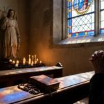 Zbliżenie starszego mężczyzny modlącego się w kaplicy, przed nim figura św. Rafała obok zapalonych świec