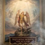 Obraz malowidła ściennego przedstawiający wizerunek Świętego Michała Archanioła z mieczem i tarczą w rękach, w tle niebo z dwoma innymi archaniołami w oddali