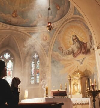 Sylwetka osoby modlącej się w kościele, na ołtarzu kościoła widnieje wizerunek Trójcy Świętej i Boga Ojca
