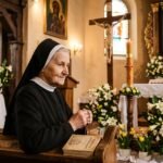 Obraz starszej kobiety modlącej się w kościele z różańcem, Biblią w rękach i w tle obrazem Chrystusa otoczonego białymi kwiatami