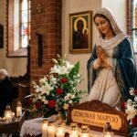 Wnętrze kościoła parafialnego z widokiem na ołtarz, na którym znajduje się figura Matki Boskiej otoczona białymi kwiatami i zapalonymi świecami.